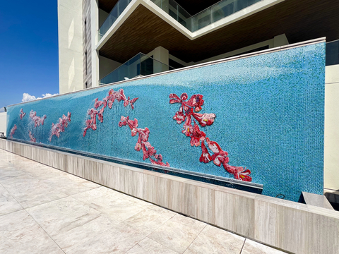 The floral motif, drawing from the majestic Jacaranda Tree at the entry roundabout, adds a distinctive touch, with pink/purple flowers serving as both decorative elements and a visual break in the ocean-themed composition front waterfall feature. The front mosaic mural, spanning 60 feet wide by 11 feet high and comprising over 600,000 hand-placed mosaic pieces, showcases Corral's unique craftsmanship and distinctive use of oversized handmade mosaic Smalti pieces. (Photo: Business Wire)