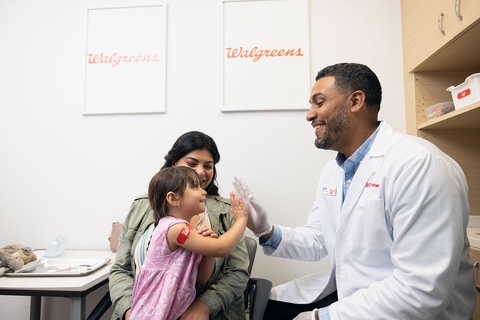 Young patient high-fives pharmacist after vaccination at Walgreens (Photo: Business Wire)