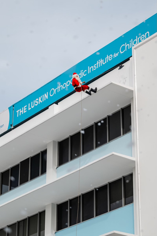 original Santa Claus rappels down the Luskin Medical Pavilion wall at the 35th Annual Luskin Orthopaedic Institute for Children Toys & Joy Holiday Party to give over 1,000 patients and families gifts for the holidays. Photo credit, Danny Liao