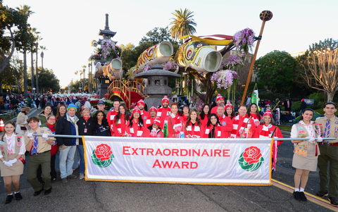 The 2025 OneLegacy Donate Life float honorees pose in front of the banner that announced the Extraordinaire Award on the 2025 Rose Parade. Young honoree Jaylee Bou-Silverio is wearing a beenie on the first row, and Roza Saad is wearing glasses. (Photo: Business Wire)