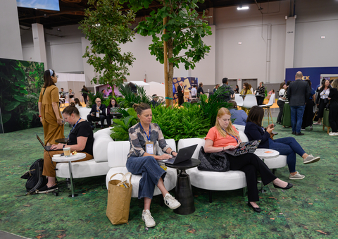 "Attendees at IMEX 2024 relax and work in a nature-inspired lounge area, where lush greenery and modern seating provide a comfortable space for networking and productivity amidst the bustling event." (Photo: Business Wire)