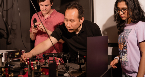 original Boston University College of Engineering Associate Professor Jerry Chen, center, with senior scientist Andrew Blaeser to the left, and former undergraduate research assistant Rhea Singh to the right, working with a Quadroscope, a custom, two-photon mesoscope. Credit: Christopher McIntosh.