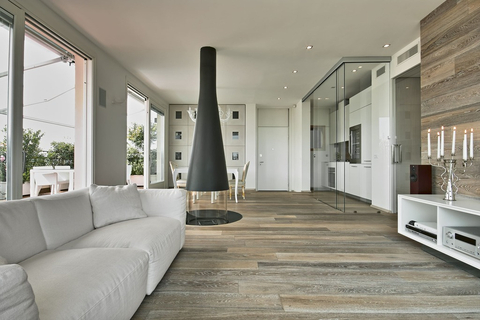 Modern open-concept living space with sleek wood flooring and a minimalist fireplace, showcasing high-quality renovations by AGM Renovations. (Photo: Business Wire)