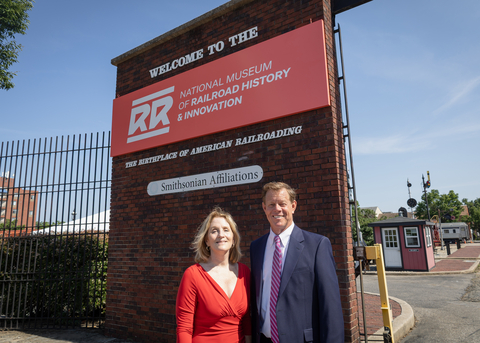 Kris Hoellen, Executive Director, and Francis Smyth, Board Chair, stand in front of the newly installed sign for the National Museum of Railroad History & Innovation.