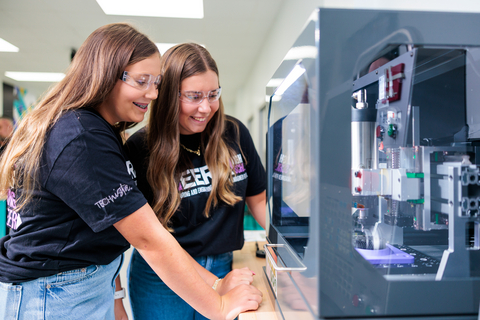 original Middle school students watch a CNC (Computer Numerical Control) machine.