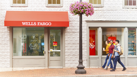 original Wells Fargo storefront with red awning and pedestrians walking by on a brick sidewalk.