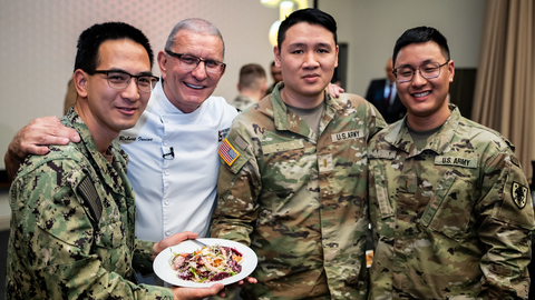 Chef Robert Irvine (center), founder of the Robert Irvine Foundation, joins U.S. military service members. Through the Foundation's new "Fuel to Serve" partnership with USAA, Irvine is working to use food and shared meals as entry points to strengthen military family well-being and readiness.
