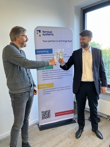 A toast to a new collaboration! Felix Gilcher, Managing Director responsible for Ferrocene, and Stephen Head, Chief Executive Officer of Universal Signalling, celebrate their partnership to develop the first Rust-based railway certification package.